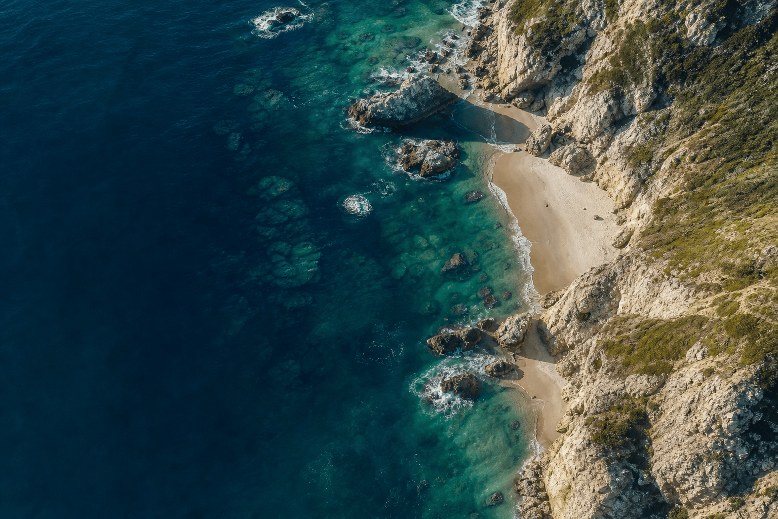 Top-down Atlantic coastline with deep blue water and pale sand